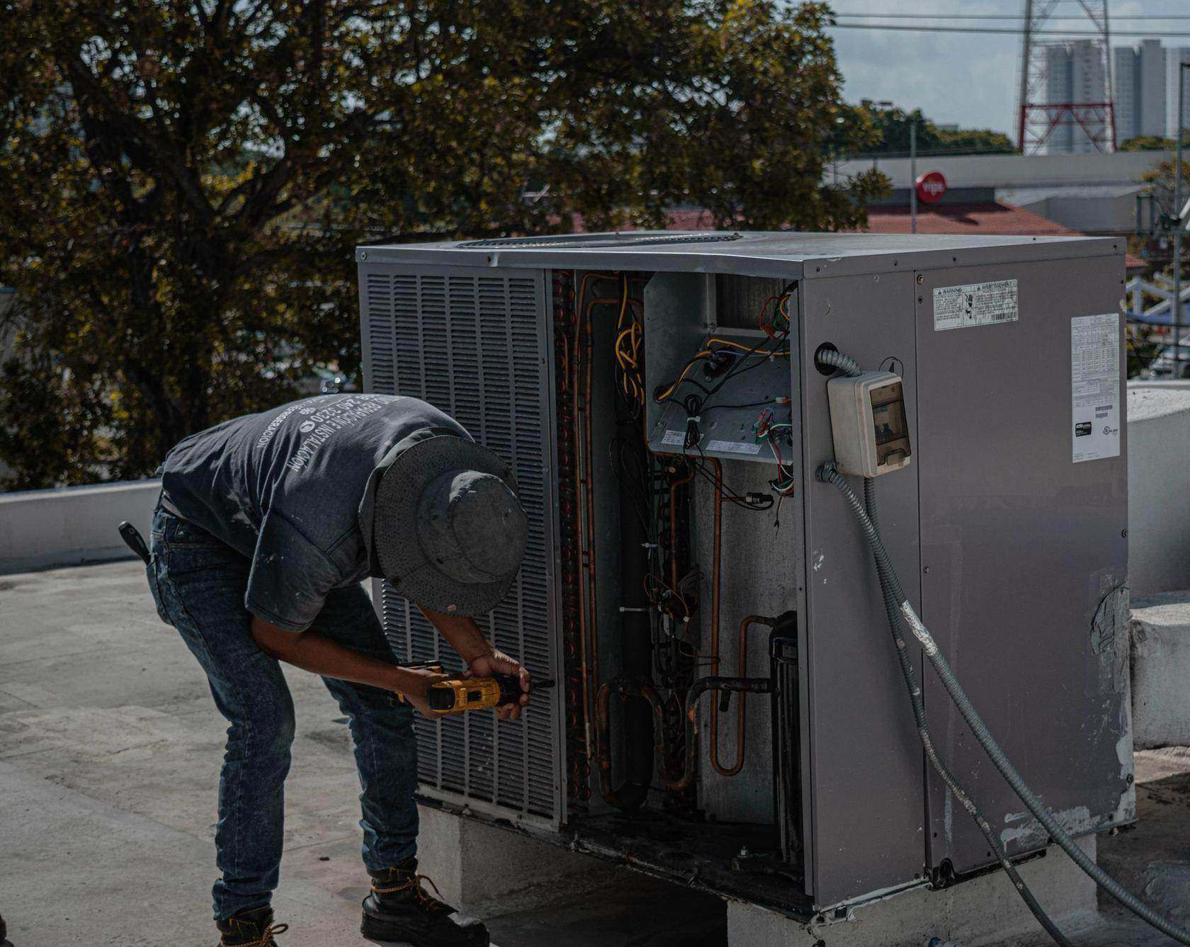 Técnico de ar condicionado fazendo manutenção em unidade externa em cobertura
